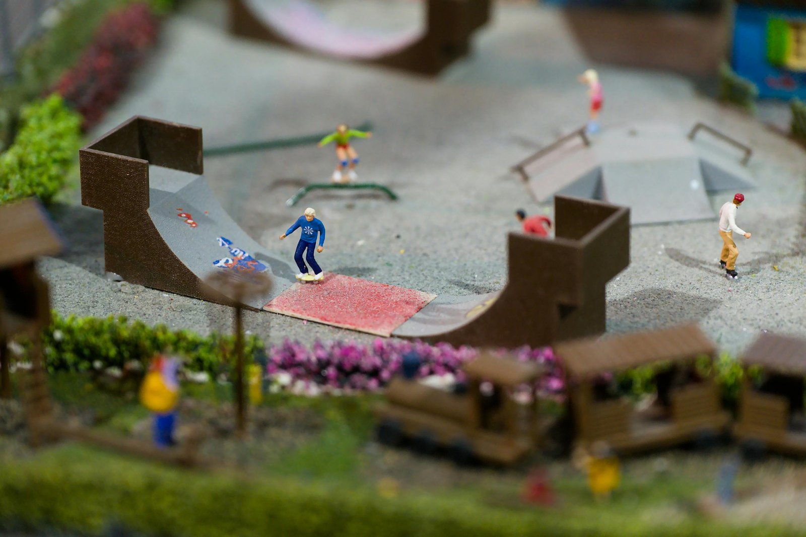 Miniature world with skateboard park featuring detailed figurines engaged in various skateboarding activities.