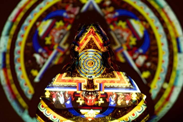 Vivid projection of a mandala on a figure, creating a colorful and mystic effect.